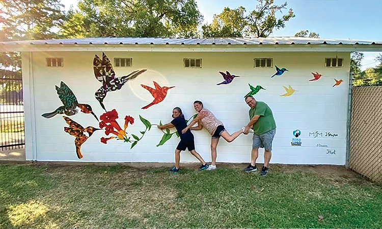 Bastrop is an official ‘Bird City,’ so it’s apropos that the mural at 1200 Willow St. features hummingbirds. It was painted in 2020 by, from left, Maria Montoya Stayton, Theresa Dawson and Jeffrey Stayton. Photo courtesy of Maria Montoya Stayton.